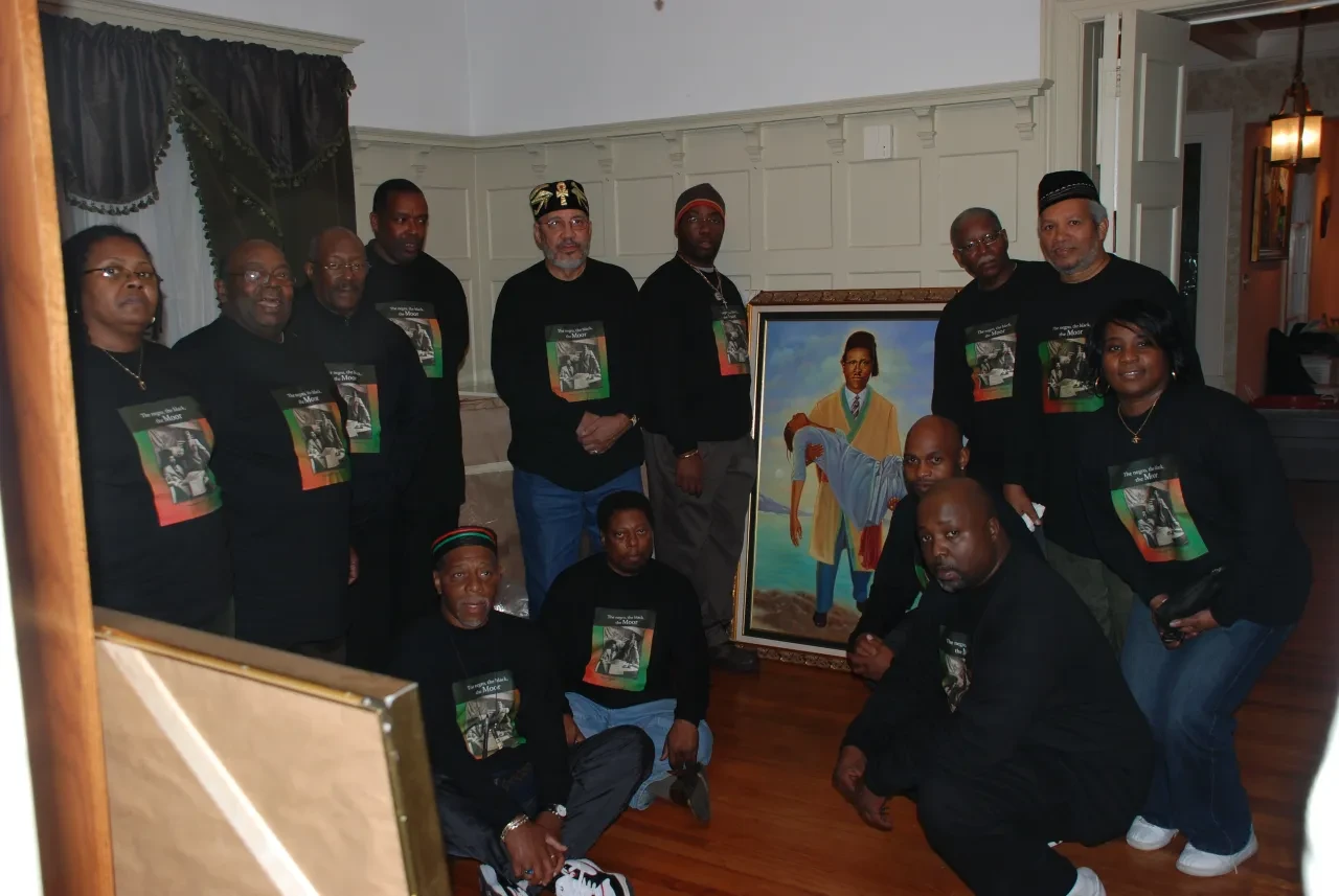 Group gathered around a framed portrait indoors